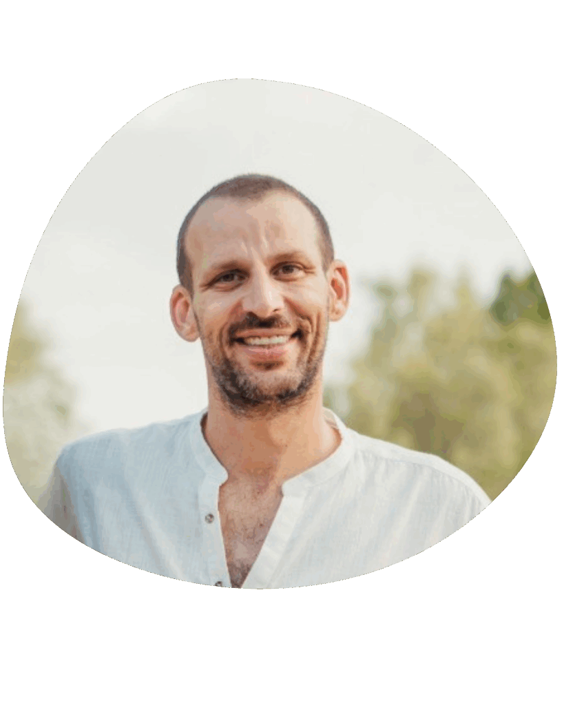 שלמה לב, מגשר מוסמך, עומד בחוץ עם שיער קצר וזקן, לובש חולצה בהירה. מאחוריו עצים שמסביבם שמיים בהירים.