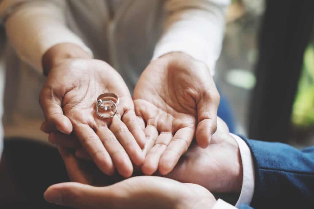 שלוש ידיים כפופות מחזיקות שתי טבעות כסף, מרמזות על רגע סמלי או טקסי, אולי בתחילת מסע או במהלך יעוץ גירושין.