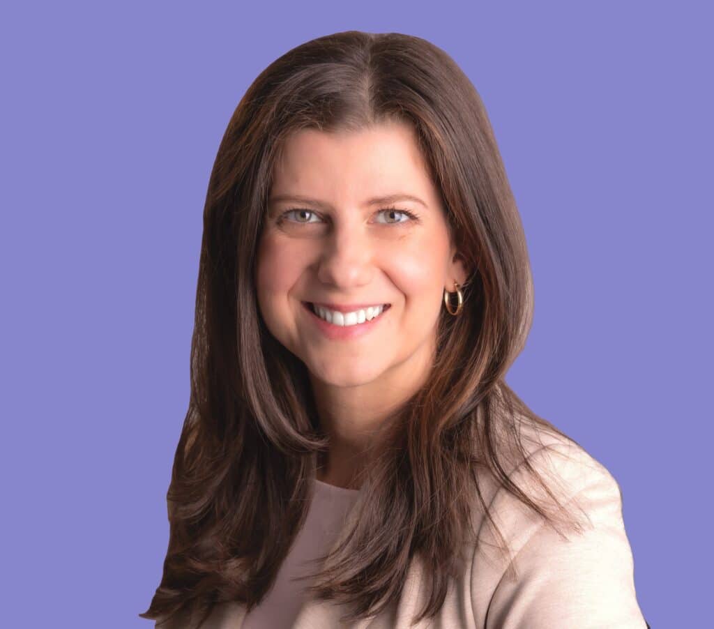 עדי שרון, יועצת מומחית לתכנון פיננסי, מחייכת למצלמה עם שיער חום ארוך ובלייזר בהיר, על רקע סגלגל עדין.